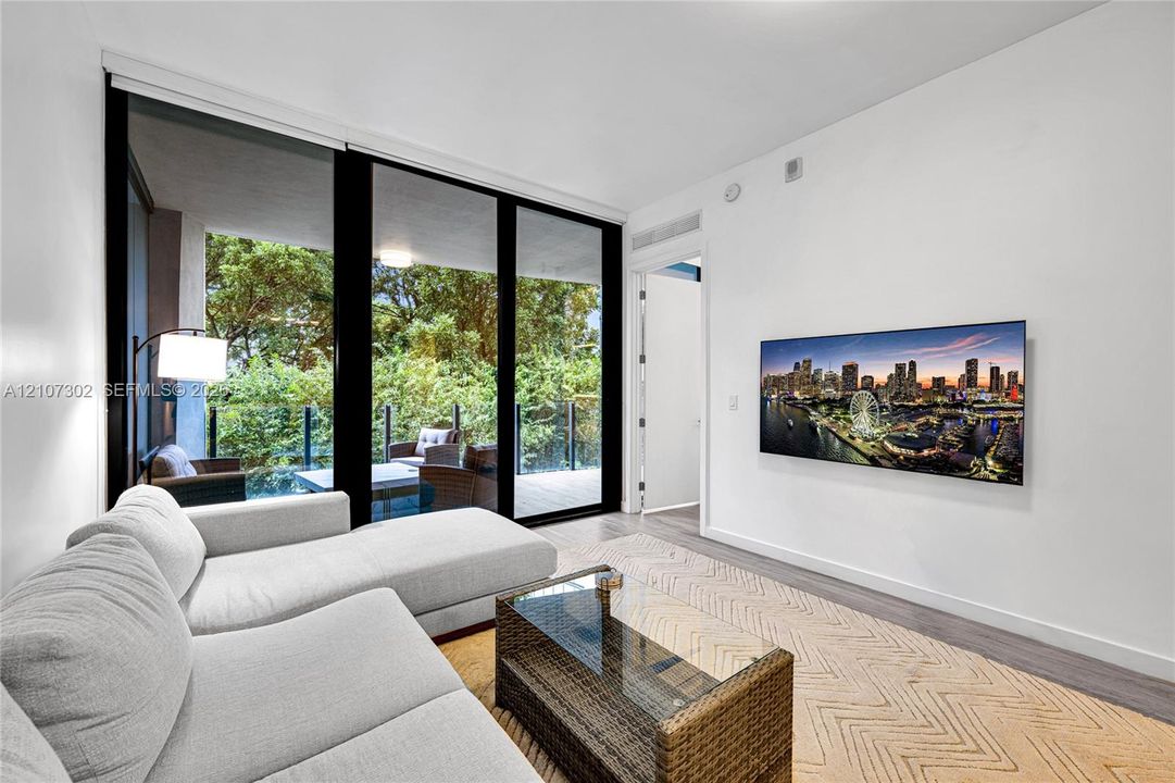 Floor-to-ceiling glass sliding doors, wood-finish flooring, and a private balcony with glass railing