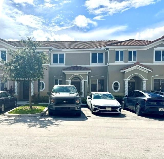 Multi-family exterior featuring a terracotta tile roof, stucco facade, spiral column entryway details, and decorative oval windows