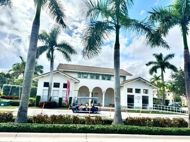 Stucco exterior featuring a covered arched entryway, clay tile roof, and mature palm trees