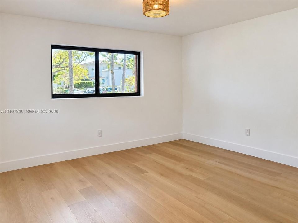 Room featuring wood-finish flooring, white walls, black-framed horizontal window, and a woven drum light fixture