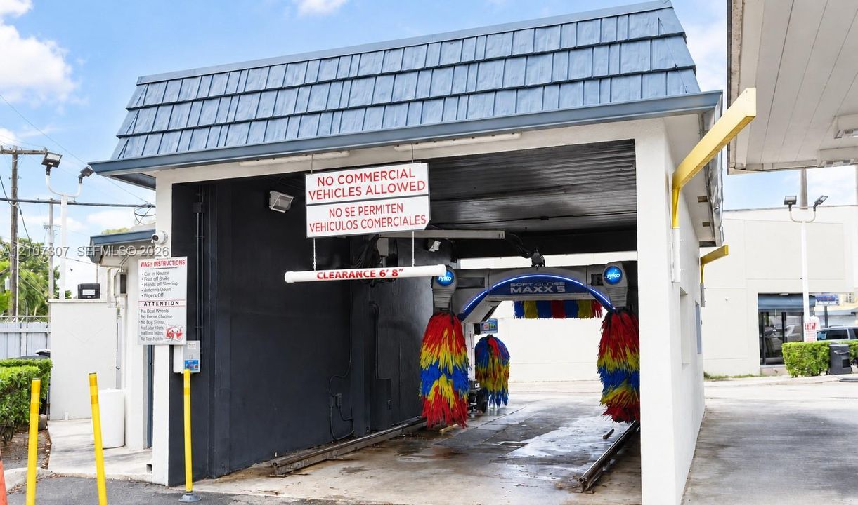 Automated car wash facility featuring a covered bay with built-in cleaning machinery, rail-guided track system, and reinforced concrete structure