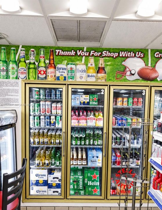 Commercial triple-door refrigeration unit featuring glass-panel doors, gold-toned frames, and internal wire shelving