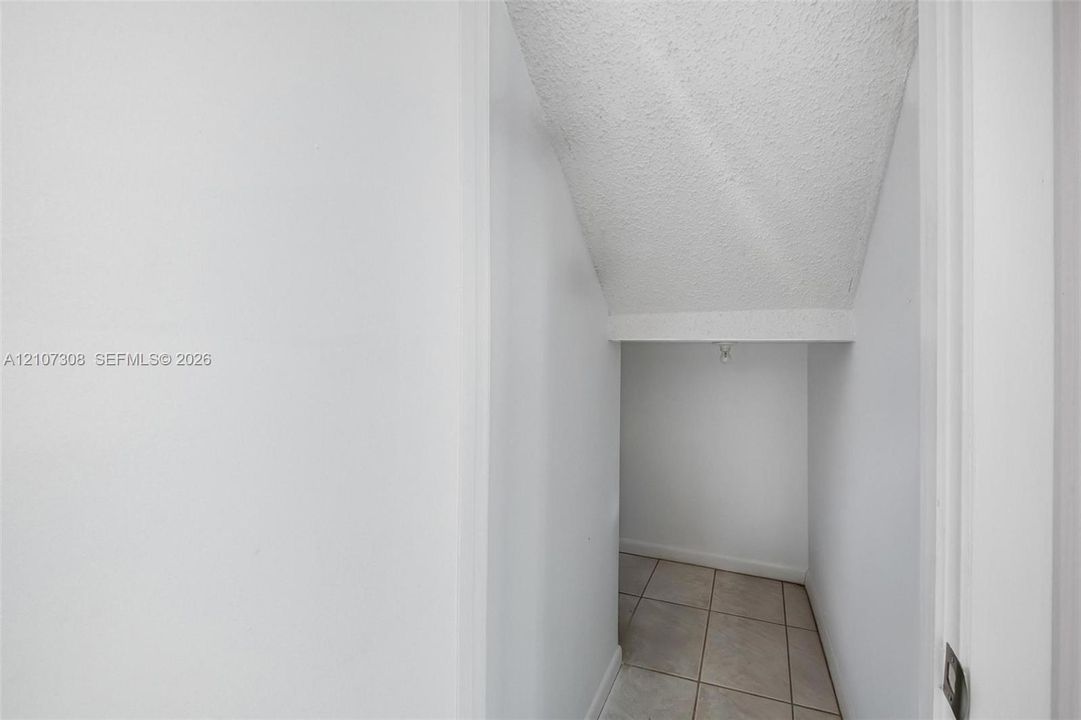 Storage alcove featuring ceramic tile flooring, neutral wall finishes, and a textured ceiling