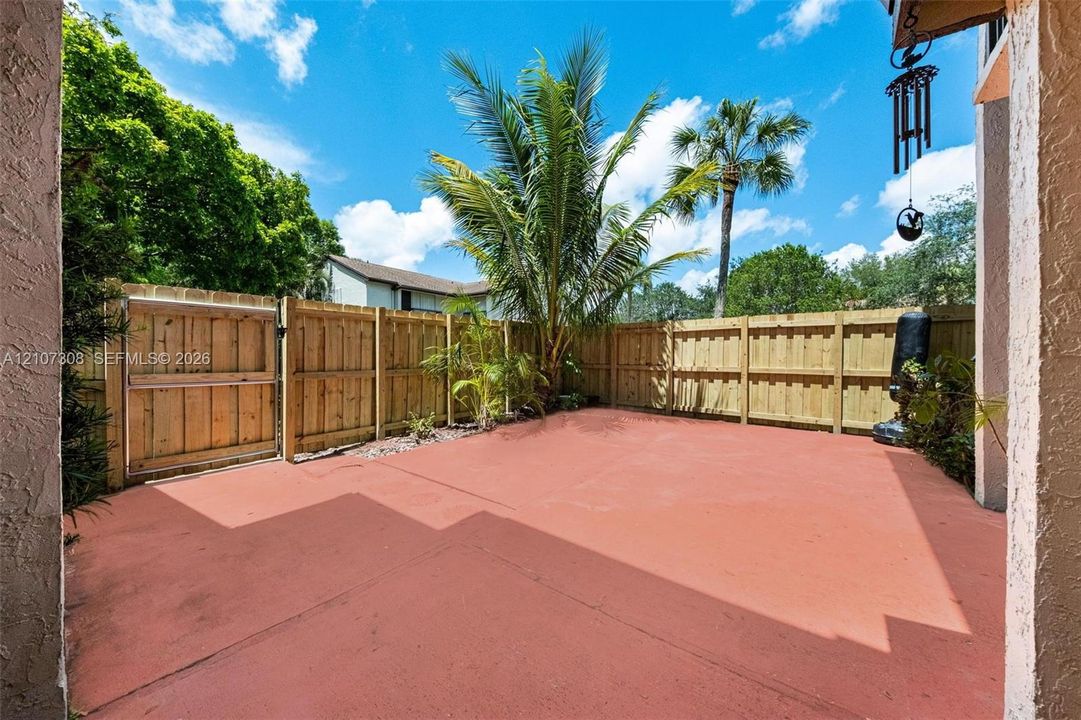 Entry spacious patio featuring a concrete surface, wood-slat privacy fencing, and exterior sliding glass doors