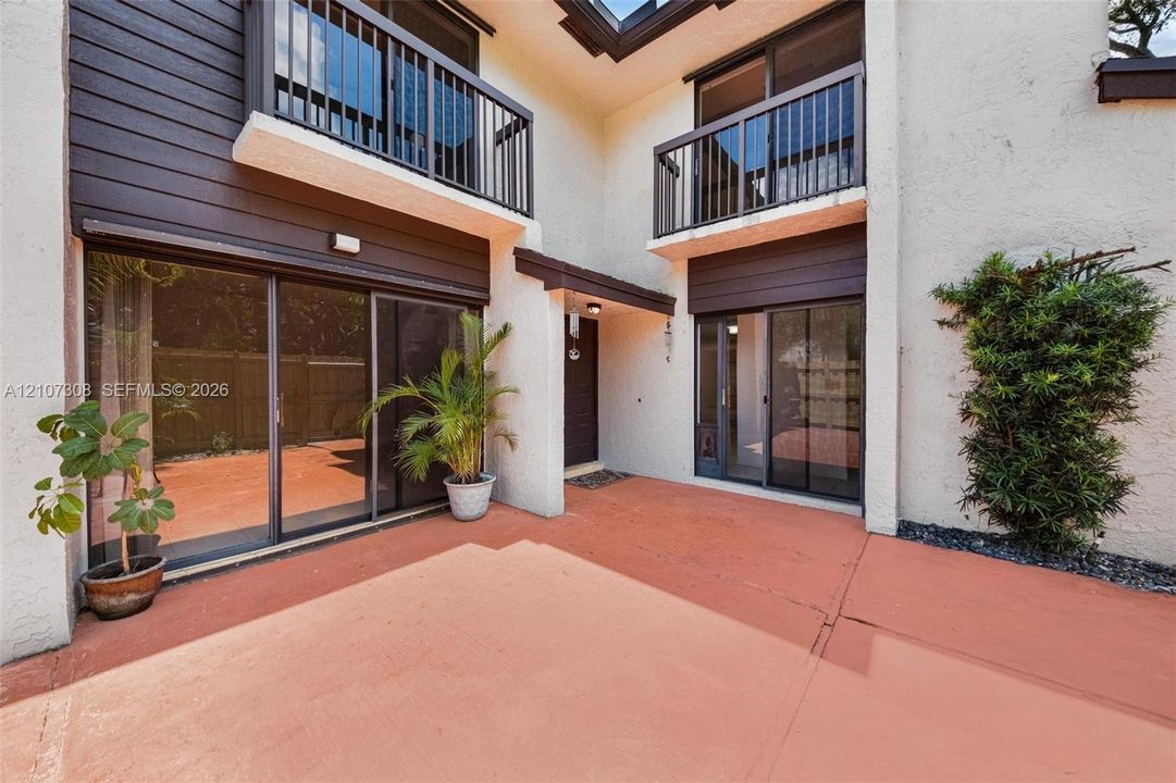 Entry spacious patio featuring a concrete surface, wood-slat privacy fencing, and exterior sliding glass doors