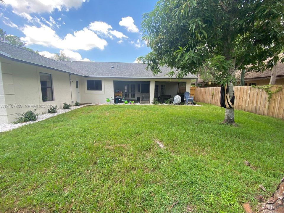 Stucco exterior featuring a covered patio, lawn space, and wood privacy fencing