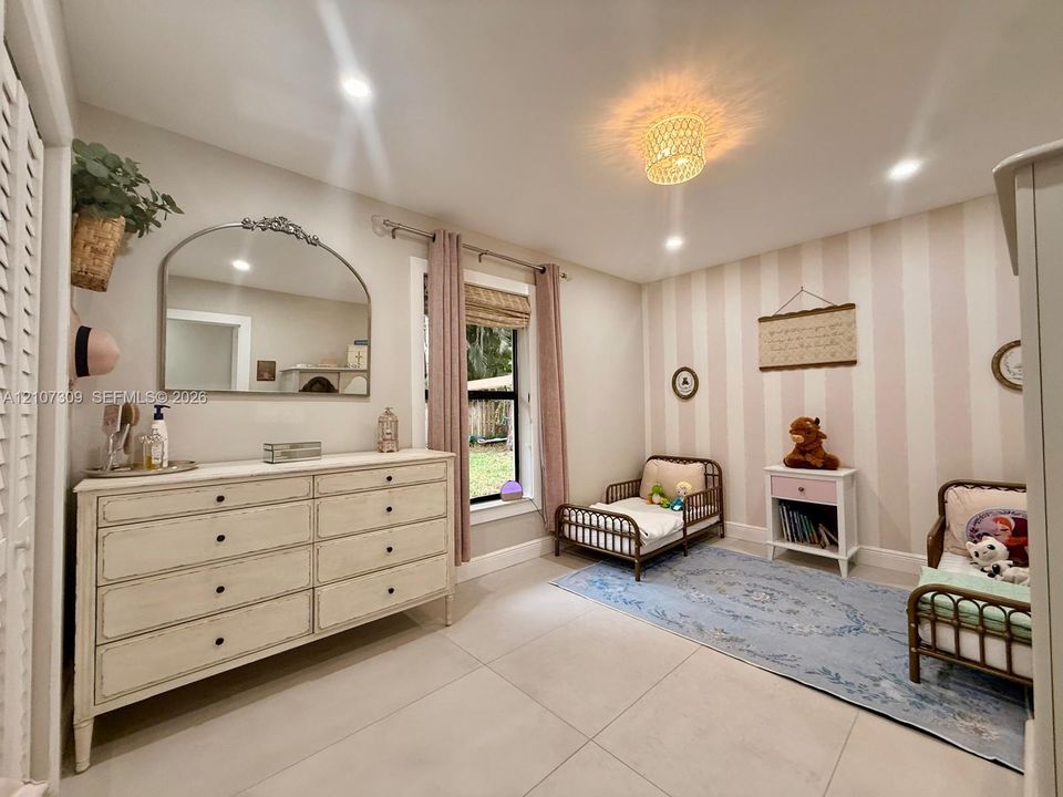 Neutral-toned large-format tile flooring, recessed lighting, decorative woven flush-mount ceiling fixture, and vertical striped wallpaper accent wall