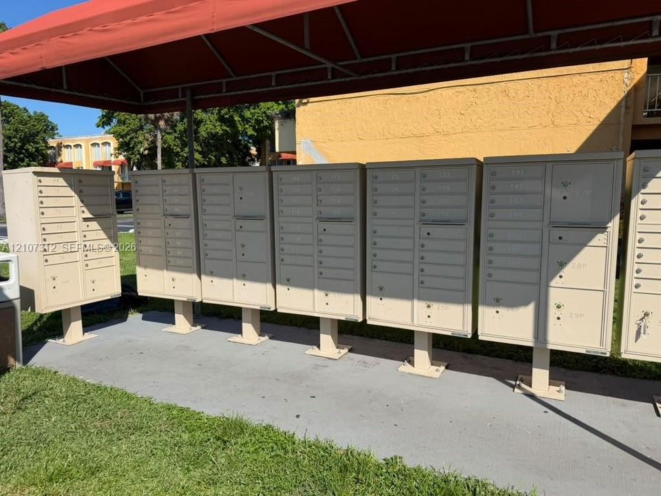 Centralized metal mailbox bank featuring individual locking compartments and a protective overhead canopy