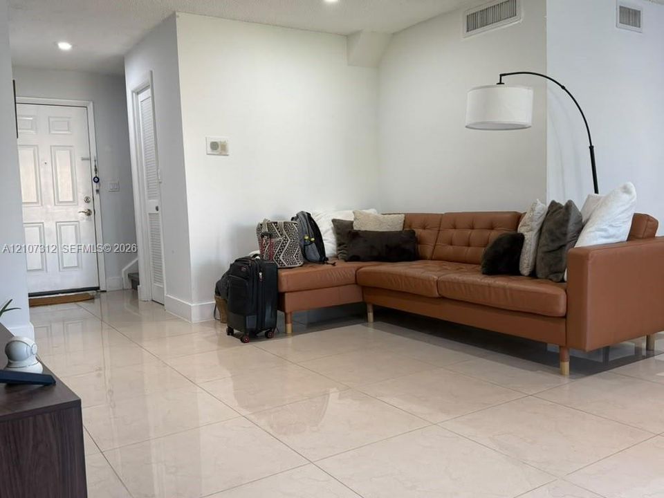 Large-format tile flooring, recessed ceiling lighting, and a six-panel entry door