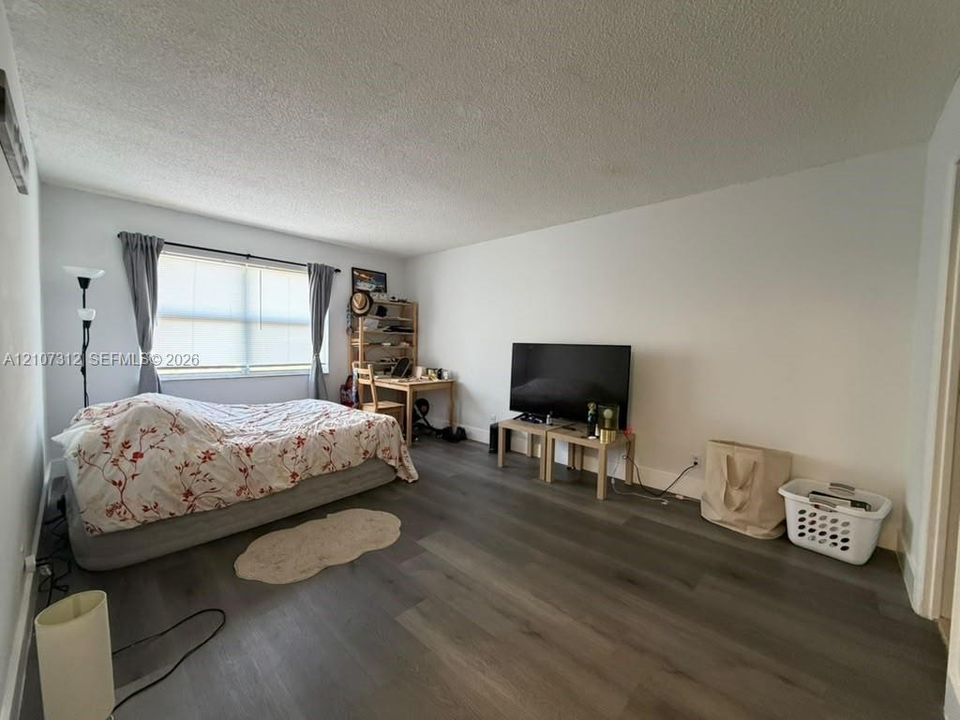 Living space featuring wood-finish flooring, neutral walls, and a large window with natural lighting