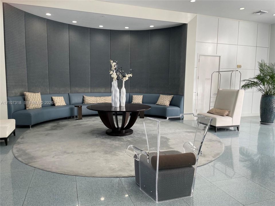 Curved wall with charcoal-toned grid-patterned paneling, polished stone flooring, and recessed ceiling lighting