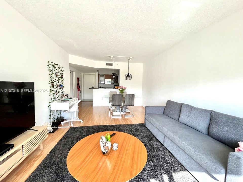 Open-concept living space featuring wood-finish flooring, a kitchen breakfast bar, and pendant lighting
