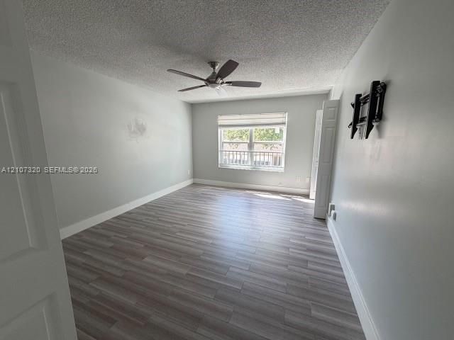 Wood-finish flooring, ceiling fan with light fixture, window with exterior railing, and dual-panel interior doors