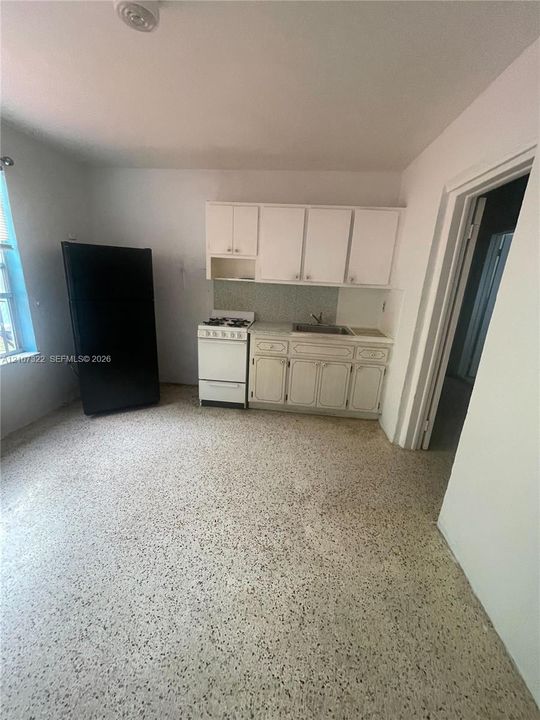 Kitchen featuring terrazzo flooring, white cabinetry, integrated stainless steel sink, and a built-in gas range