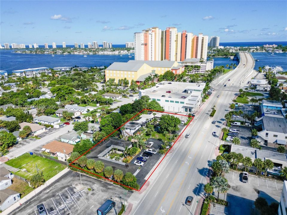 Aerial perspective of a multi-unit property featuring a central courtyard, paved surface parking, and perimeter landscaping