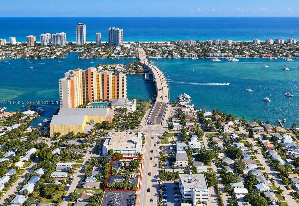 Aerial perspective of property featuring mature perimeter landscaping, paved onsite parking, and a prominent location in a coastal setting