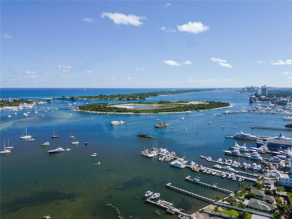 Aerial perspective of coastal landscape featuring expansive waterways, maritime dock infrastructure, offshore islands, and distant ocean horizon
