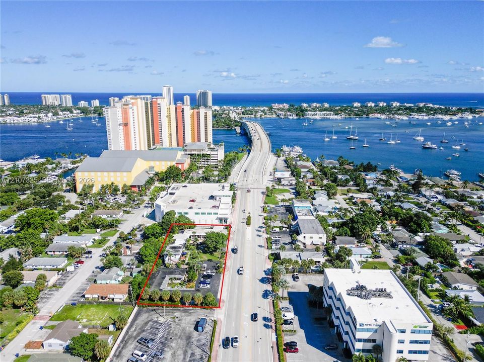 Aerial perspective of a parcel featuring mature landscaping, paved surface parking, and perimeter palm trees