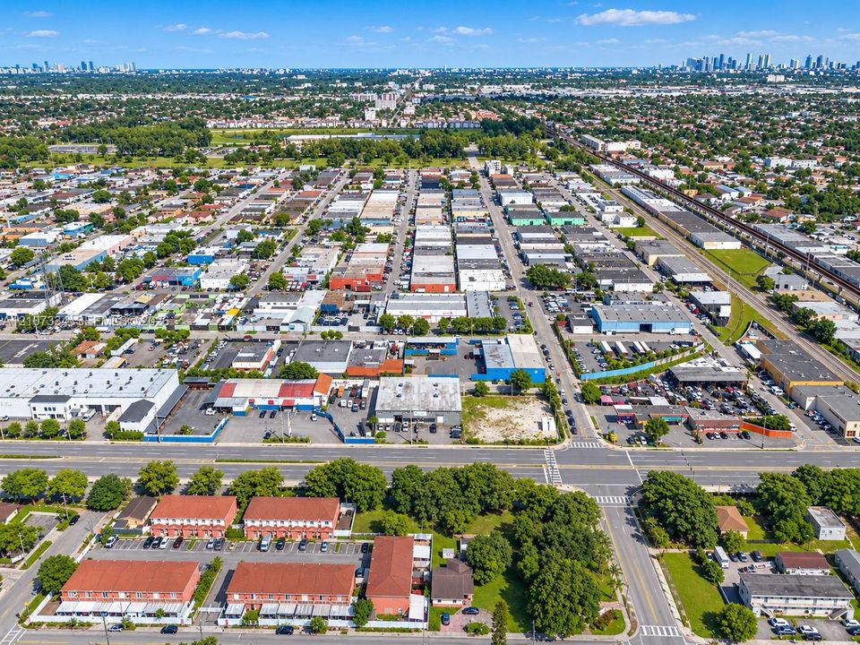 Aerial perspective featuring multi-unit red-roofed residential structures, established tree canopy, and immediate proximity to major regional thoroughfares and urban infrastructure
