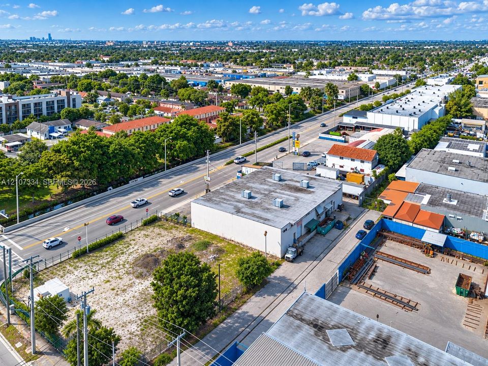 Industrial property featuring a rectangular structure, expansive paved lot, fenced perimeter, direct street frontage, and HVAC rooftop units