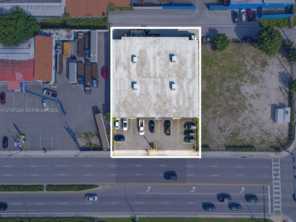 Aerial perspective of a commercial property featuring a flat roof with roof-mounted HVAC units and a paved parking lot with marked stalls