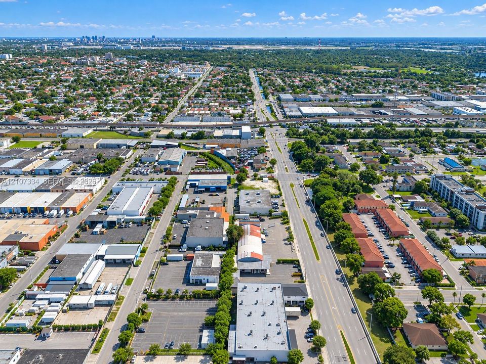 Aerial perspective of a multi-parcel industrial and commercial site featuring extensive paved parking, multiple warehouse buildings with flat roofing, and direct frontage on a major thoroughfare