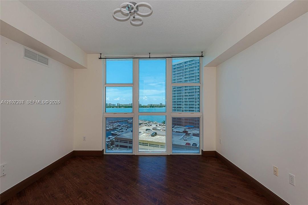 Floor-to-ceiling windows, wood-finish flooring, and modern multi-ring ceiling lighting