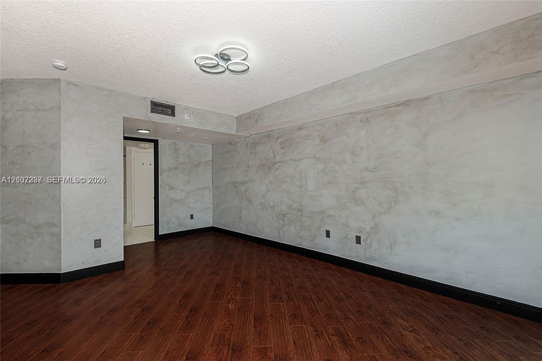 Interior room featuring wood-finish flooring, decorative marble-patterned wall finishes, and a modern circular multi-ring flush-mount light fixture