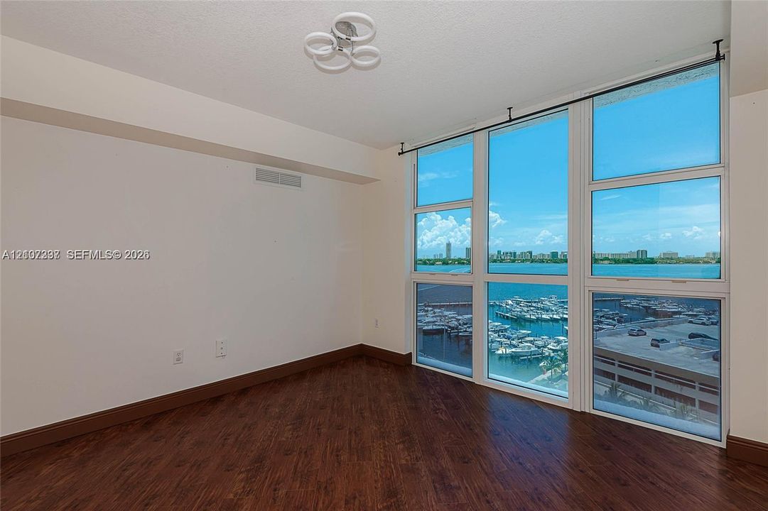Floor-to-ceiling windows, wood-finish flooring, and modern multi-ring flush mount lighting