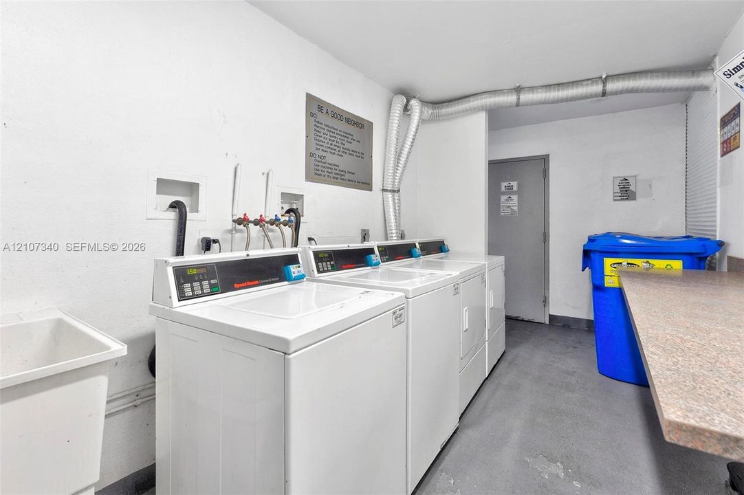 Utility area featuring a deep basin utility sink, multiple laundry appliances, and a laminate-surface folding counter