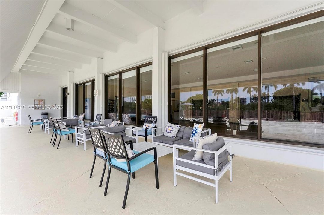 Covered patio featuring a smooth concrete finish, white exposed beam ceiling, and extensive sliding glass wall panels