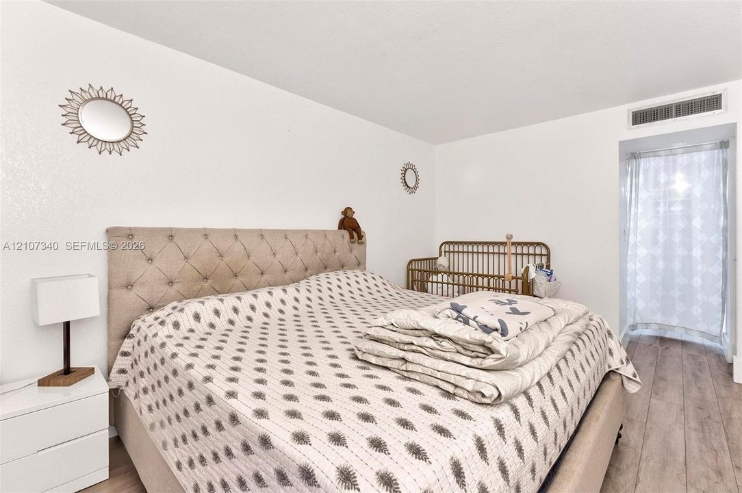 Room featuring wood-finish flooring, smooth-finish white walls, and a tall arched doorway