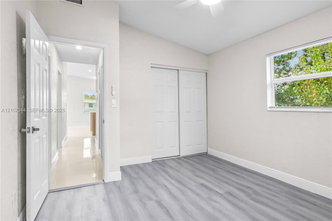 Interior room featuring wood-finish flooring, a ceiling fan, a window with horizontal blinds, and a closet with double sliding doors