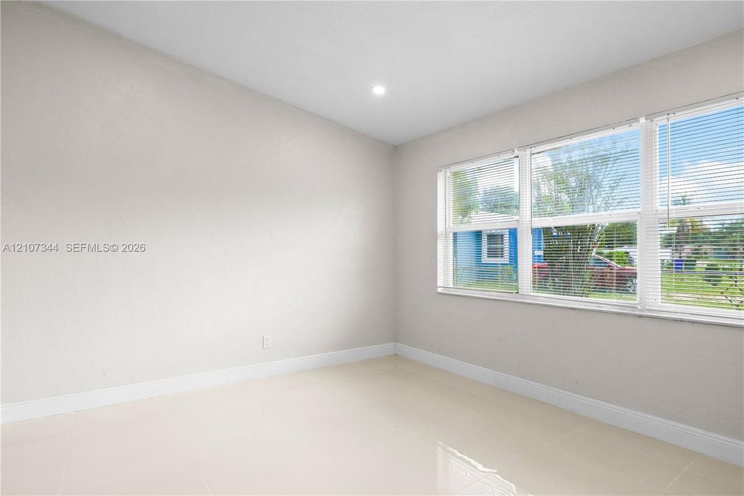 Interior space featuring neutral wall paint, polished tile flooring, and multiple windows with installed blinds