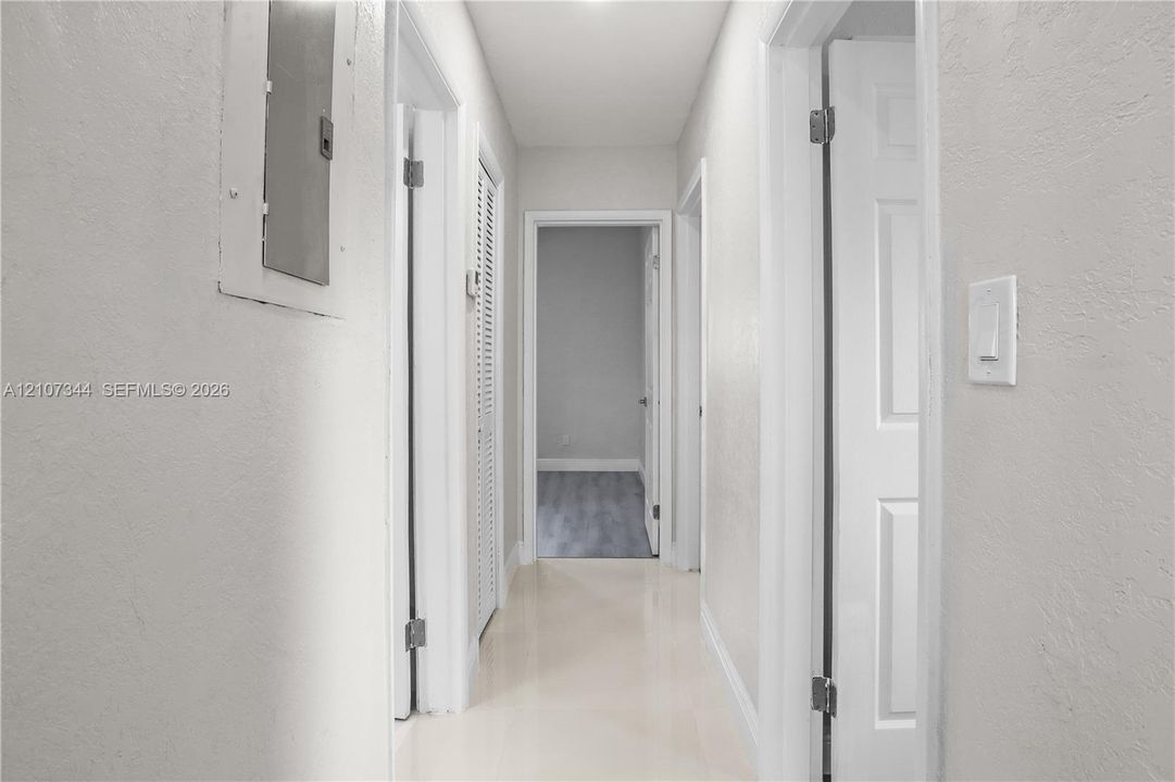 Hallway featuring neutral wall paint, multi-panel interior doors, louvered closet doors, and smooth-surface flooring