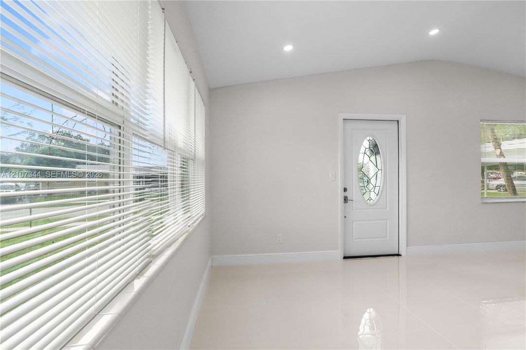 Interior space featuring large-format tile flooring, recessed lighting, and a front entry door with an oval decorative glass insert