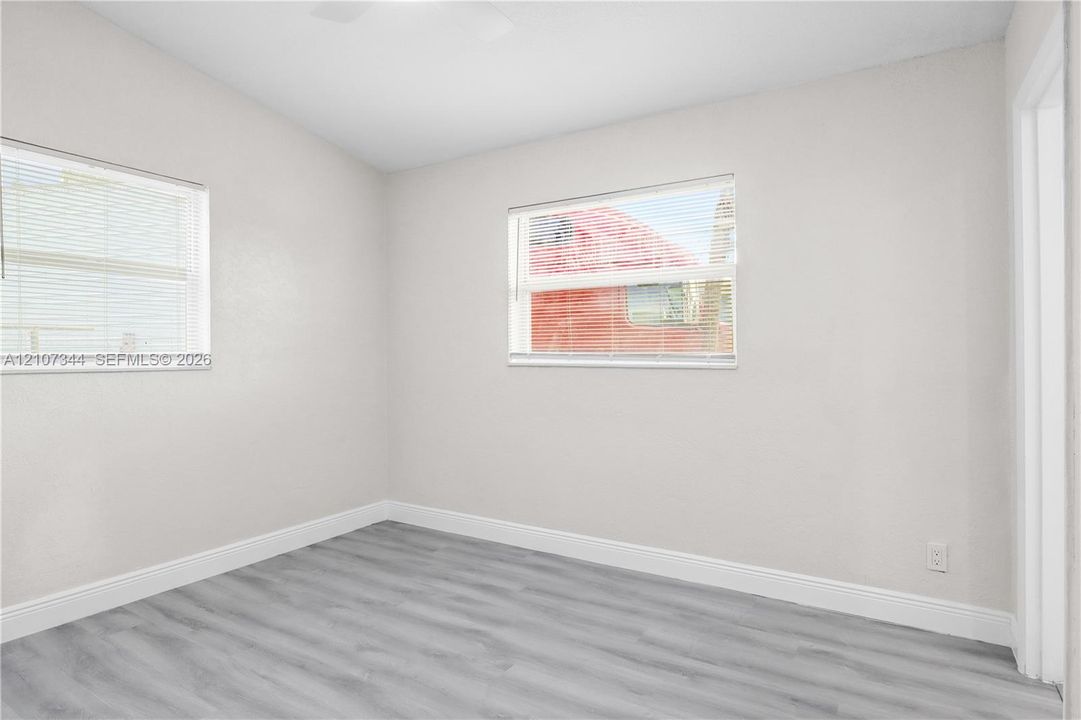 Room featuring neutral wall paint, wood-finish flooring, and dual windows with horizontal blinds