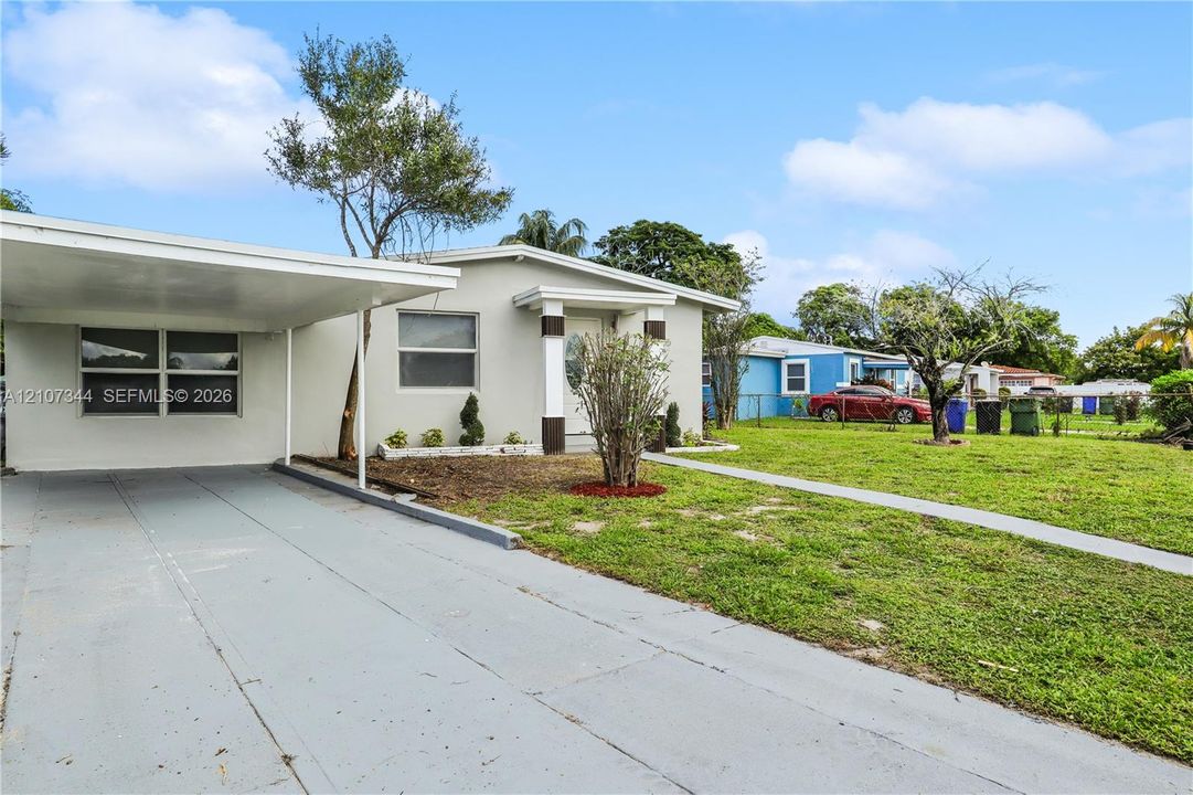 Single-story exterior featuring a concrete-paved carport, stucco siding, and a concrete walkway