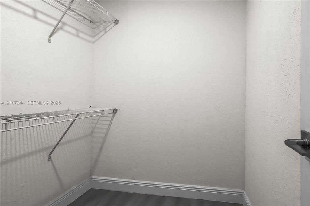 Storage space featuring dual-tier white wire shelving and grey wood-finish flooring