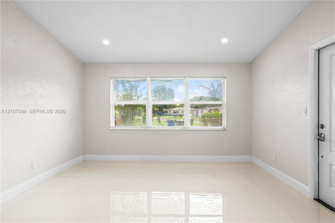 Neutral-toned interior featuring large-format tile flooring, recessed ceiling lighting, and a triple-pane window