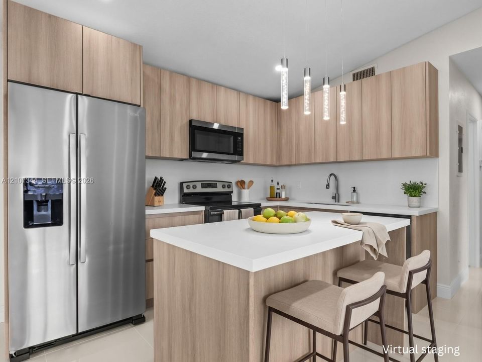 Kitchen featuring wood-finish cabinetry, quartz countertops, stainless steel appliances, a central island, and contemporary pendant lighting