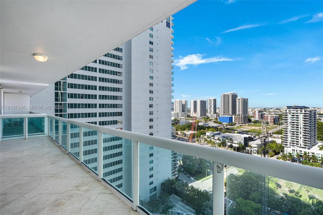 Covered balcony featuring stone flooring and a glass-paneled railing