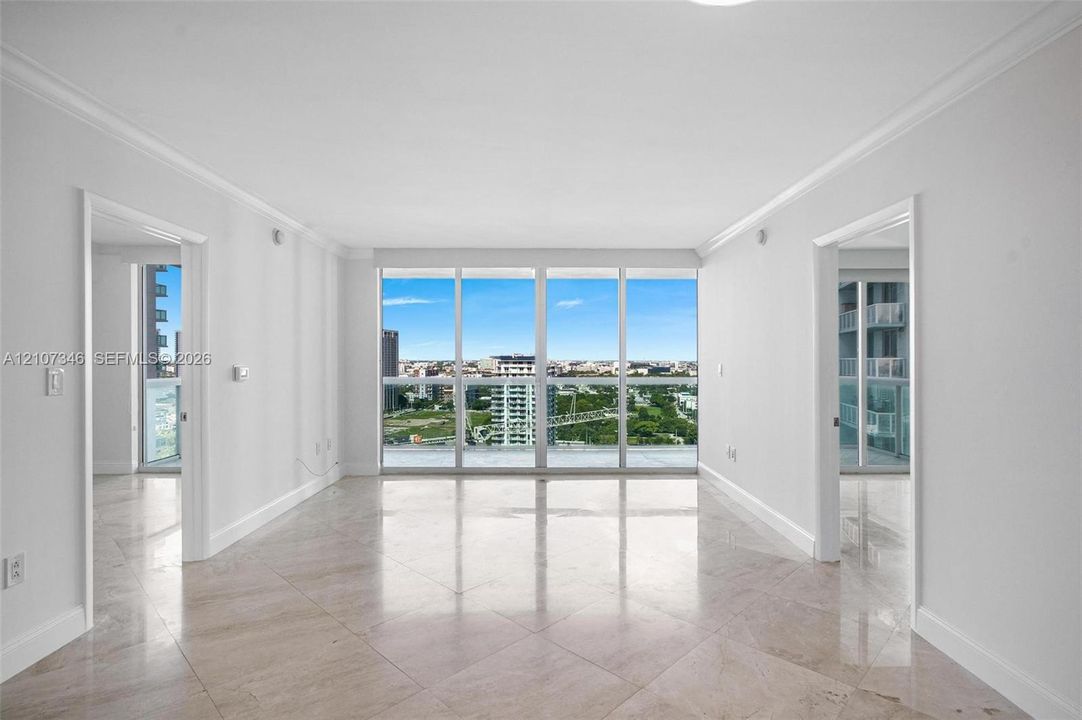 Interior space featuring floor-to-ceiling windows, polished stone tile flooring, and crown molding