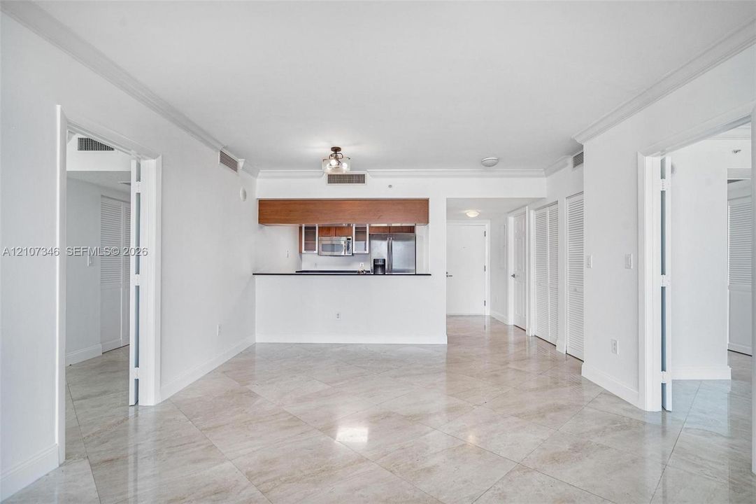 Open floor plan featuring stone-finish tile flooring, pass-through breakfast bar, stainless steel appliances, and crown molding