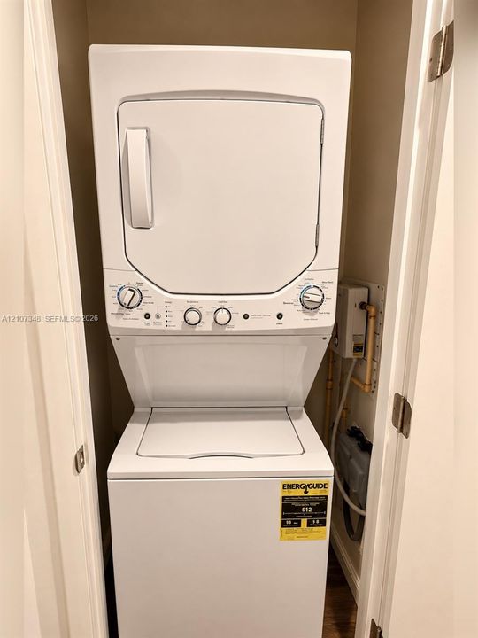 Stacked white laundry unit featuring a top-loading washer, front-loading dryer, and tactile control knobs