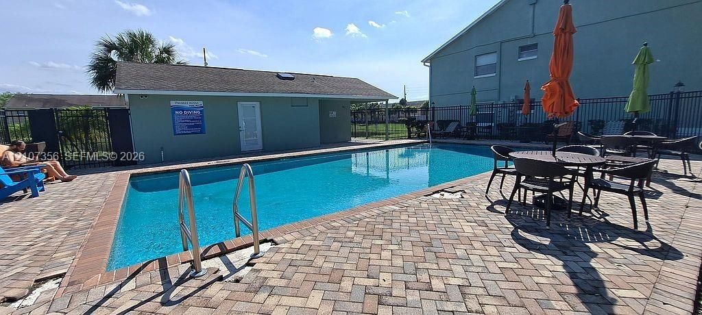 Rectangular swimming pool featuring brick paver decking and metal perimeter fencing