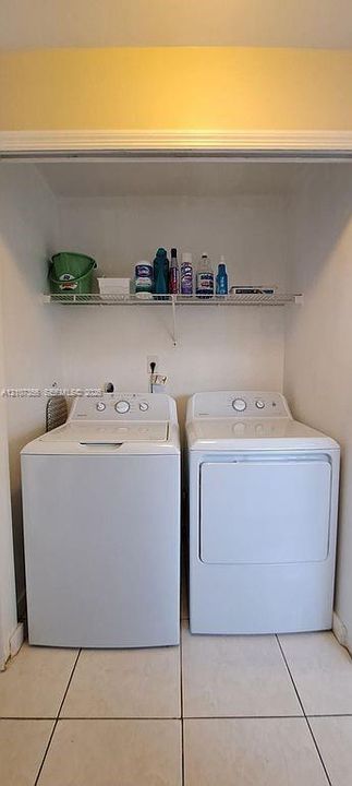 Laundry alcove with Nearly New Appliances featuring white tile flooring and a wall-mounted wire storage shelf