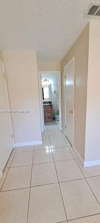 Bathroom Look from Bedroom Neutral tile flooring throughout with matching interior doors