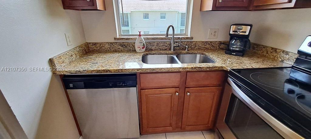 Kitchen featuring stone-finish countertops, stainless steel dual-basin sink with a gooseneck faucet, wood cabinetry, and stainless steel dishwasher