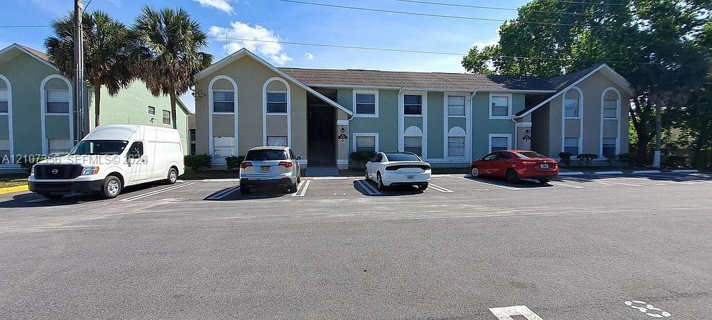 Two-story exterior facade featuring light-toned stucco finish, arched window accents, and paved off-street parking            (2 Assigned Parking Spots)